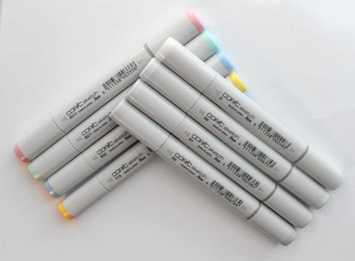 For grey Copic markers and for pastel Copic markers stacked on the table.