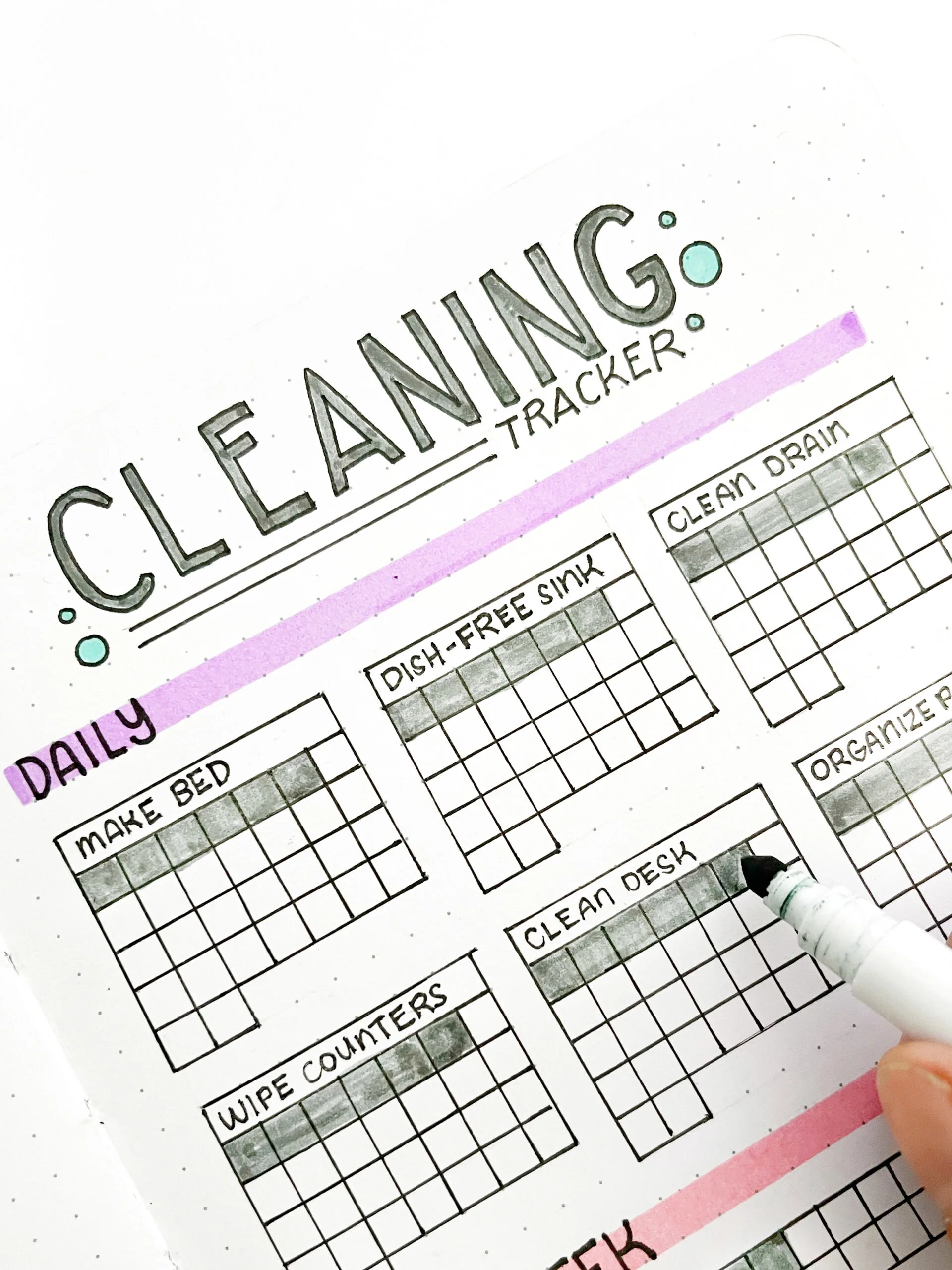 Logging a cleaning chore in the cleaning tracker using a pencil in a bullet journal.