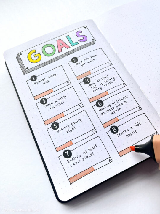 A highlighter fills out progress bars on a goal tracking layout in a bullet journal.